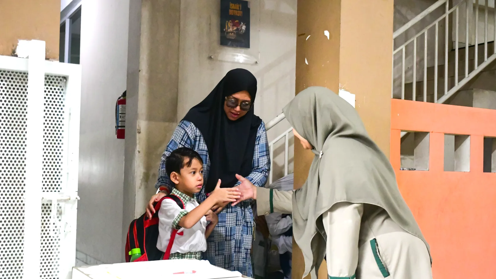 Guru menyambut anak dan orang tua di pintu masuk sekolah